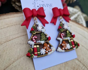 May include: A pair of Christmas tree earrings with red bows. The trees are decorated with gingerbread men, candy canes, presents, and holly. The earrings are made of polymer clay and have gold accents.