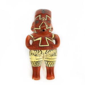 May include: A terracotta figurine of a person with geometric patterns painted in yellow and black. The figurine has a red-brown body and a whistle in its mouth.