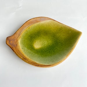 May include: A green and brown ceramic leaf-shaped dish with a crackled glaze.