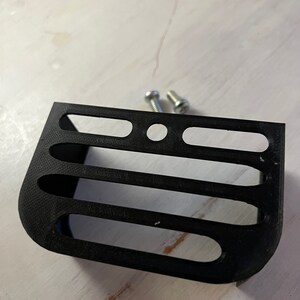 May include: A black plastic 3D printed shelf with four slots and a round hole in the center. Two silver screws are included.