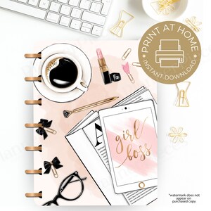 May include: A pink and gold planner with the text "girl boss" on a tablet screen. The planner is surrounded by coffee, lipstick, glasses, and other office supplies.