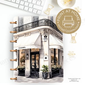 May include: A printable planner page featuring a watercolour illustration of a Parisian storefront with a white awning and the word "CHANEL" displayed on the building. The storefront has a black door and windows with floral displays. The image is suitable for use as a planner page or for printing and framing.