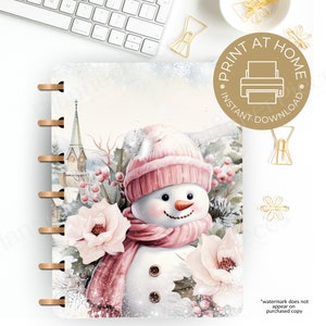 May include: A printable planner cover featuring a watercolor illustration of a snowman with a pink hat and scarf, surrounded by pink flowers and a snowy winter scene.