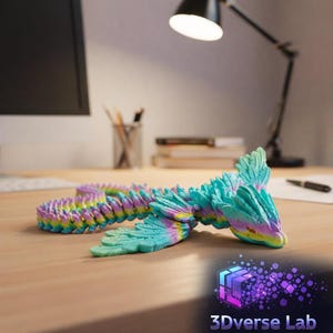 May include: A colorful, articulated dragon toy in shades of blue, green, yellow, and purple, resting on a wooden surface. The dragon has a detailed, textured design and is positioned near a desk lamp and a computer monitor. The logo for 3Dverse Lab is visible.