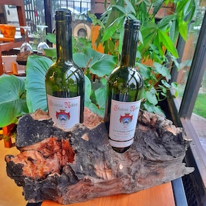 Può includere: Due bottiglie di vino Cabernet Sauvignon Chateau Nobles, annata 2019, esposte in un portabottiglie in legno rustico.
