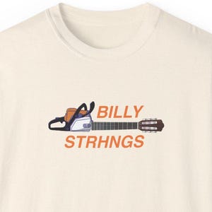 May include: A white t-shirt with a graphic of a chainsaw and guitar with the text "BILLY STRHNGS" printed on it.