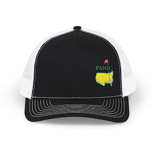 Peut inclure: Casquette de camionneur noire et blanche avec une visière incurvée. Le panneau avant est noir avec le mot "PANIC" au-dessus d'un graphique de carte verte et jaune avec un drapeau rouge. L'arrière de la casquette est en mesh blanc.