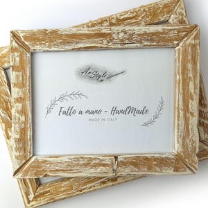 Puede incluir: Dos marcos de fotos rectangulares de madera con un acabado envejecido en blanco roto y marrón. Los marcos tienen un interior blanco con el texto "Fatto a mano - Handmade MADE IN ITALY" y un logotipo.