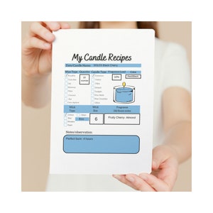 May include: A handwritten candle recipe card with a blue and white illustration of a candle. The card lists the ingredients, quantities, and notes for a Black Cherry scented candle. The recipe calls for 16 ounces of soy wax, 10% fragrance load, and a wick size of 6. The notes indicate a perfect burn time of 4 hours.