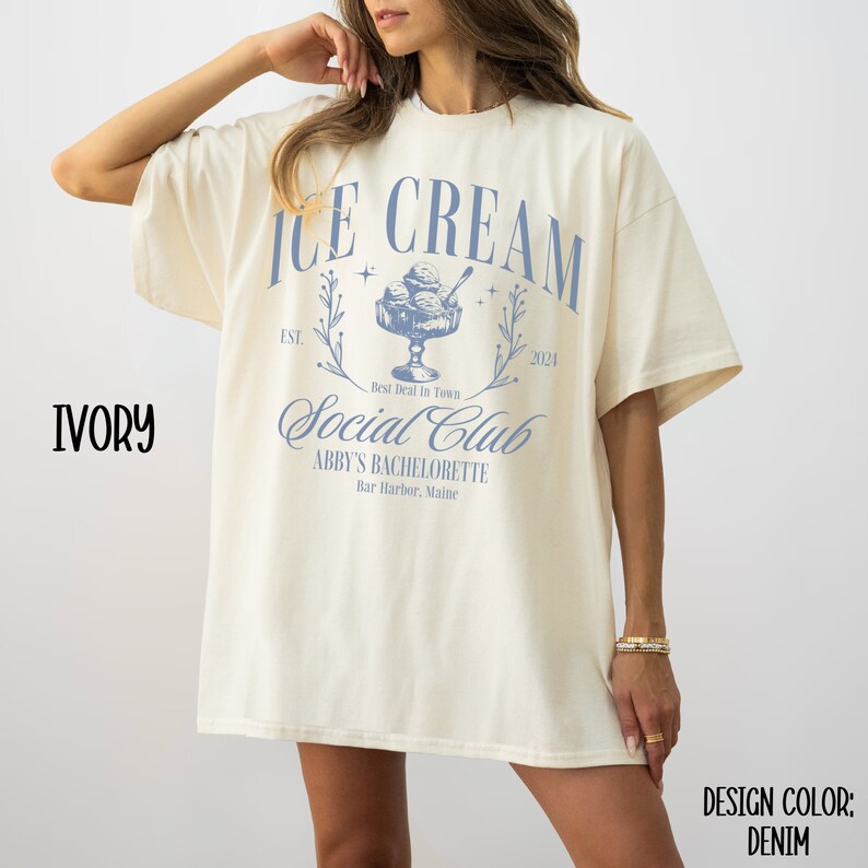 May include: Ivory t-shirt with a blue graphic design that says "Ice Cream Social Club" with the text "Est. 2024" and "Abby's Bachelorette Bar Harbor, Maine".