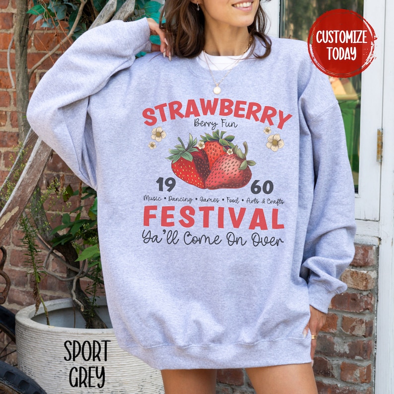 May include: Grey sweatshirt with a red and white strawberry graphic. The text "STRAWBERRY Berry Fun" is above the strawberries. The text "19 60 Music Dancing Games Food Arts & Crafts FESTIVAL Ya'll Come On Over" is below the strawberries.
