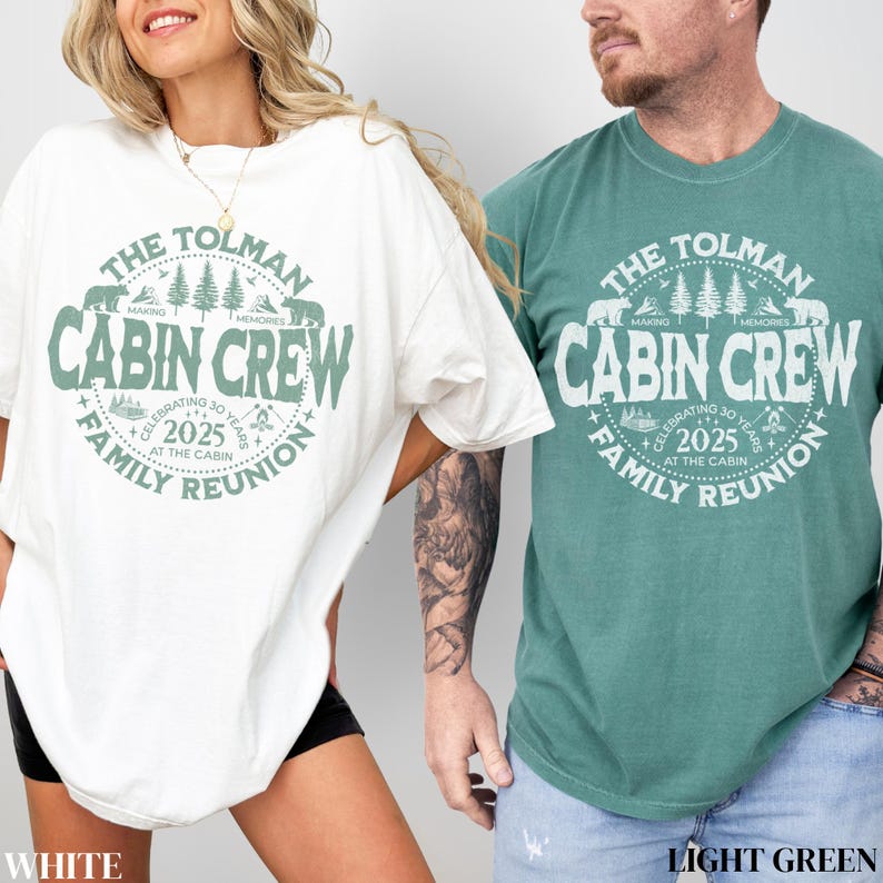 May include: Two t-shirts, one white and one light green, featuring a circular design with the text "THE TOLMAN CABIN CREW FAMILY REUNION 2025". The design includes bears, trees, and the words "MAKING MEMORIES".