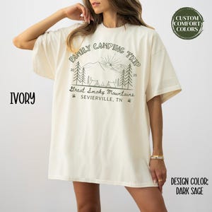 May include: Ivory-colored t-shirt with a "Family Camping Trip" graphic featuring mountains, trees, and the text "Great Smoky Mountains, Sevierville, TN." The design includes the numbers 20 and 25. The design color is dark sage.