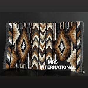 Könnte beinhalten: Rechteckige Sattelunterlage mit einem geometrischen Muster in Braun-, Weiß-, Grau- und Schwarztönen. Die Unterlage hat ein zentrales Rautenmuster und Chevron-Muster. Der Text "MRS INTERNATIONAL" ist sichtbar.
