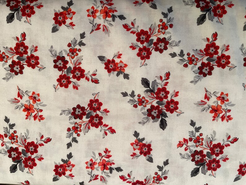 May include: White fabric with a repeating pattern of red and gray floral sprigs. The flowers are small and have a simple design.