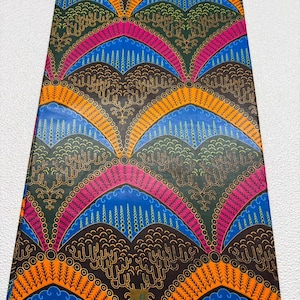 May include: A rectangular piece of fabric featuring a repeating pattern of arched shapes in vibrant orange, bright blue, and magenta against a dark brown background. The design includes intricate line work and the text M 291105 GUARANTEED.
