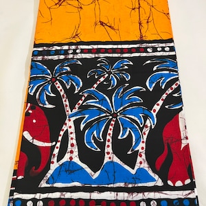 Könnte beinhalten: Ein schwarzer und orangefarbener Batikstoff mit einem Muster aus Palmen und Elefanten. Der Stoff hat einen weißen Rand mit roten und blauen Punkten. Der Stoff ist mit "Veritable Antique Batik" gekennzeichnet.
