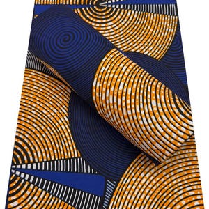 May include: A vibrant fabric with a repeating pattern of concentric orange and black circles on a navy blue background. White dotted lines and blue rectangular shapes add contrast. The fabric is rolled up, showcasing the design.