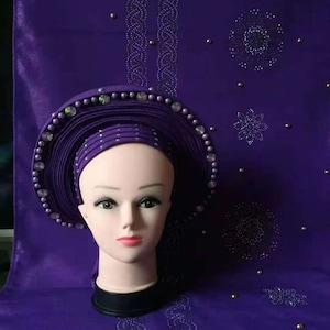 May include: A purple headwrap with a beaded design and a mannequin head wearing it.