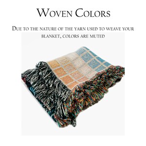 May include: A woven blanket with a geometric pattern in shades of blue, orange, and white. The blanket has a fringe border.