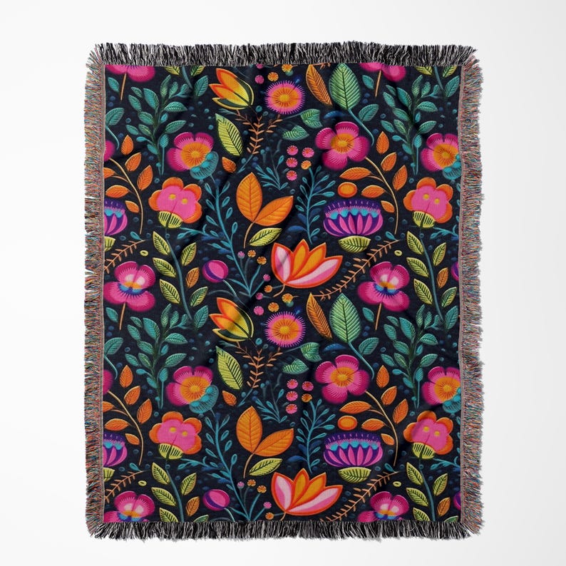 May include: A woven throw blanket with a colorful floral pattern on a dark blue background. The pattern features pink, orange, yellow, and green flowers and leaves.
