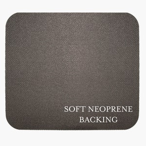 May include: A close-up of a dark gray mouse pad with the text "SOFT NEOPRENE BACKING" printed in white.