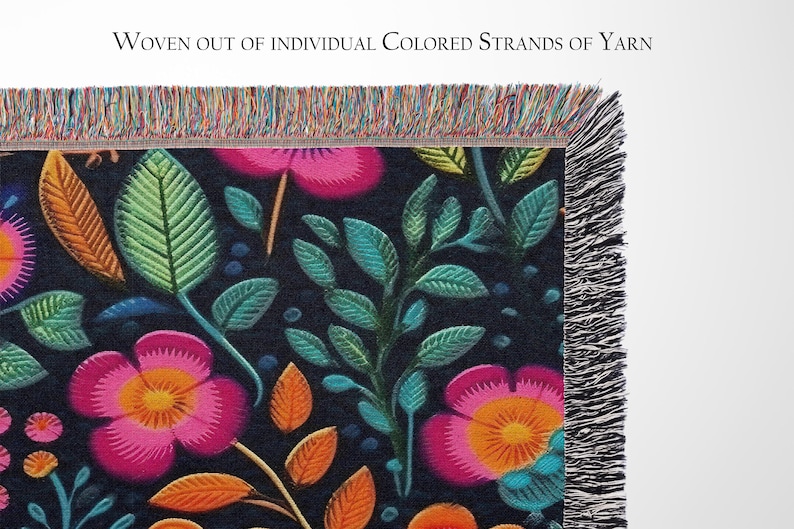 May include: A woven tapestry throw blanket with a floral pattern featuring pink, orange, and green flowers on a dark blue background. The blanket has a fringe border.