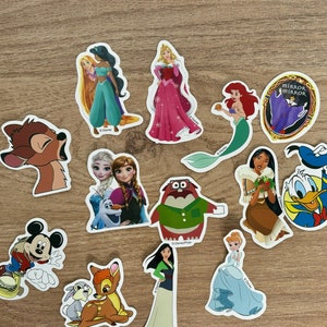 May include: A collection of Disney character stickers featuring princesses, animals, and villains. The stickers are colourful and feature various characters from Disney films, including Cinderella, Snow White, and Mickey Mouse.