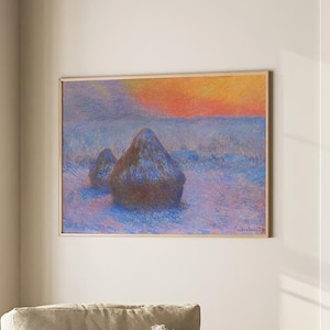 May include: A painting of a snowy landscape with two haystacks in the foreground. The sky is a vibrant orange and pink, with a hint of blue in the distance. The painting is framed in a simple wooden frame.