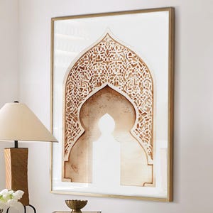 Puede incluir: Un interior con una mesa redonda de mármol sobre una base estampada, con libros y un cuenco de latón. Una obra de arte enmarcada con un diseño arqueado cuelga de la pared. Dos otomanas blancas con patas de madera están frente a la mesa. Una lámpara con pantalla beige está sobre la mesa.