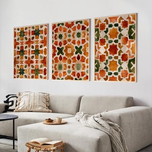 Könnte beinhalten: Drei gerahmte Aquarelldrucke mit einem geometrischen Muster in Orange-, Grün- und Beigetönen hängen über einem beigefarbenen Ecksofa. Die Drucke haben einen Holzrahmen. Ein kleiner Hocker aus Rattan und ein schwarzer Beistelltisch befinden sich vor dem Sofa.