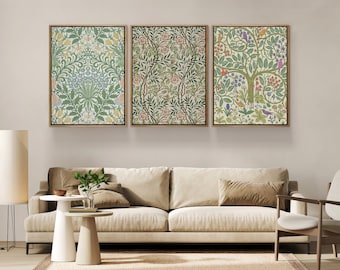 Op de afbeelding: Drie ingelijste bloemenprints in een groen-wit-roze kleurenschema. De prints hangen aan een witte muur boven een beige bank met twee kussens.