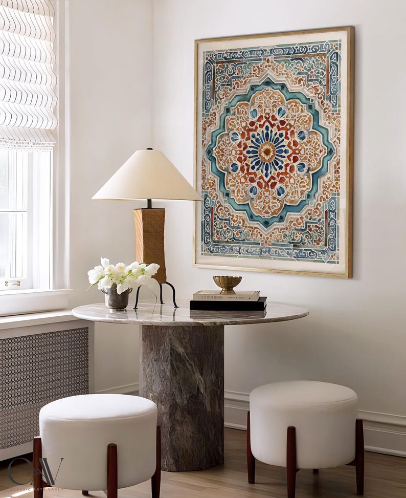 K&ouml;nnte beinhalten: Ein Raum mit einem runden Marmortisch, einem zylindrischen Sockel und zwei wei&szlig;en Ottomanen. An der Wand h&auml;ngt ein gerahmtes Kunstwerk mit einem detaillierten, farbenfrohen Design. Eine Holzlampe mit beigem Schirm und wei&szlig;e Blumen stehen auf dem Tisch.