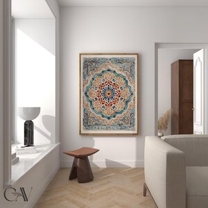 K&ouml;nnte beinhalten: Ein gerahmter Wandkunstdruck mit einem detaillierten, symmetrischen Design in Blau-, Rot- und Goldt&ouml;nen. Das Kunstwerk hat ein verziertes, geometrisches Muster und wird in einer hellen, modernen Inneneinrichtung gezeigt.