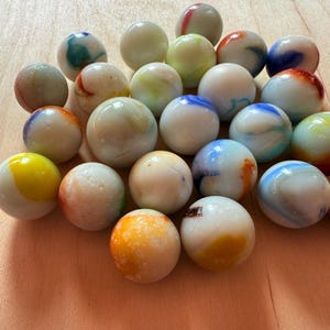 Peut inclure: Collection de billes de verre colorées. Les billes sont un mélange de couleurs, dont le blanc, le bleu, le jaune, l'orange et le vert, avec des motifs tourbillonnants. Les billes mesurent environ 2,5 cm de diamètre.