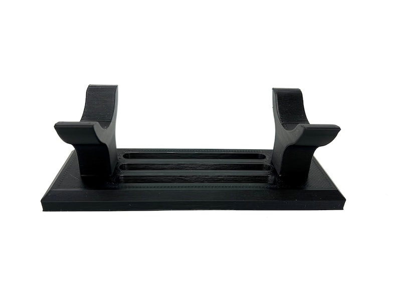 Puede incluir: Un soporte de pl&aacute;stico negro con dos brazos curvos para sostener un sable de luz. El soporte tiene tres ranuras para guardar sables de luz adicionales.