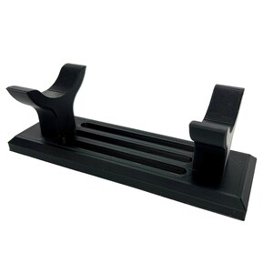 Puede incluir: Soporte de pl&aacute;stico negro con dos brazos curvos para sujetar un sable de luz u otro objeto largo. El soporte tiene tres ranuras para sujetar el objeto en su lugar.