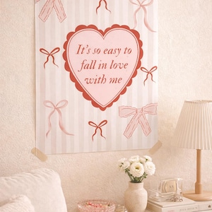May include: A poster with a pink heart-shaped design and the text "It's so easy to fall in love with me." The poster has a striped background and pink bow illustrations. The poster is taped to a wall.