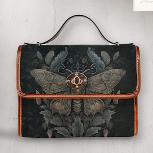 May include: A black leather handbag with a brown trim and a large moth design. The moth is surrounded by floral details and has a gold metal clasp.