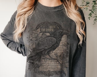 May include: A dark gray long-sleeved shirt with a vintage-style graphic of a raven and the text "Quoth the Raven" and "Edgar Allan Poe".