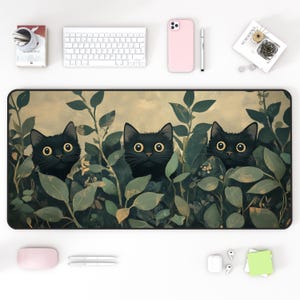 May include: A black mouse mat featuring a design of three black cats peeking out from behind green leaves. The cats have large, yellow eyes.