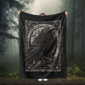 May include: Black and white tapestry featuring a raven in an ornate frame with the text "THE RAVEN". The raven is perched on a branch with its wings spread. The background is a dark forest.