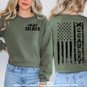 May include: Military green sweatshirt with a distressed American flag design on the back and the text "I love my soldier" on the front.