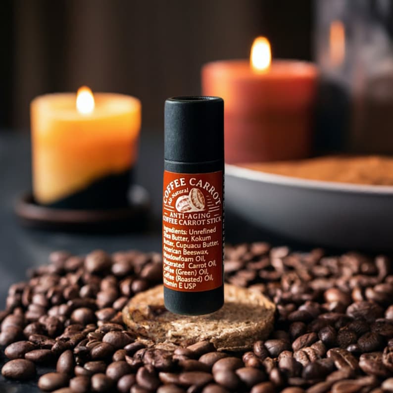 Puede incluir: Un Coffee Carrot anti-edad en barra negro y rojo, con una lista de ingredientes, se encuentra sobre una peque&ntilde;a superficie redonda y texturizada, rodeado de granos de caf&eacute;. Dos velas encendidas en el fondo emiten una luz c&aacute;lida.