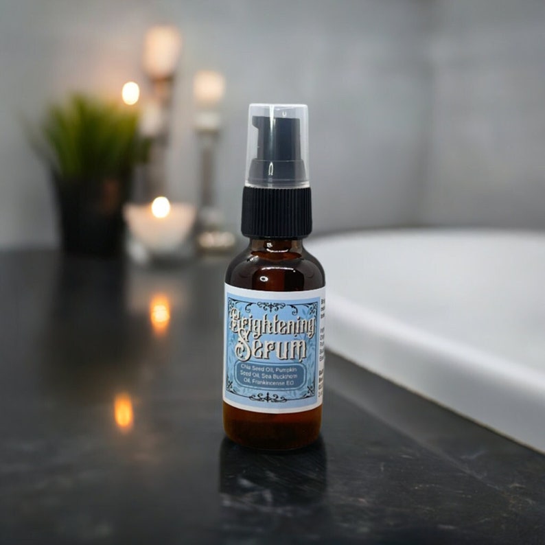 May include: A small brown glass bottle with a black pump top. The bottle is labelled "Brightening Serum" and lists the ingredients: Chia Seed Oil, Pumpkin Seed Oil, Sea Buckthorn Oil, Frankincense Oil.