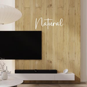 Può includere: Un moderno soggiorno con una grande televisione nera montata su una parete con pannelli di legno chiaro. La parola "Natural" è scritta in corsivo sulla parete. Un mobile bianco con una soundbar e oggetti decorativi si trova sotto la TV.