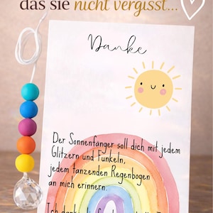 May include: A white greeting card featuring a yellow sun illustration, a watercolor rainbow, and German text. The card includes the words Danke, Ein Geschenk, das sie nicht vergisst, and a poem. A string of colorful beads with a clear crystal pendant is attached.