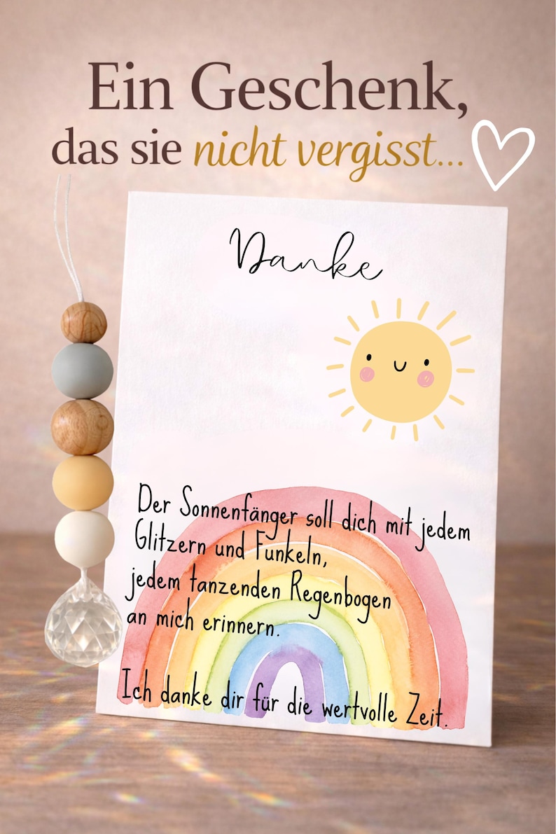May include: A greeting card with a watercolor rainbow and a smiling sun illustration. The card has German text and is accompanied by a beaded ornament with wooden and pastel-colored beads and a crystal pendant.