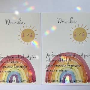 May include: Two white cards with a watercolor rainbow and a smiling sun illustration. The cards have the word "Danke" at the top and German text below. The rainbow is in shades of red, orange, yellow, green, blue, and purple.