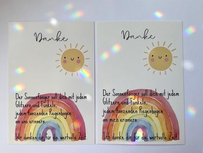 May include: Two white cards with a watercolor rainbow and a smiling sun illustration. The cards have the word "Danke" at the top and German text below. The rainbow is in shades of red, orange, yellow, green, blue, and purple.